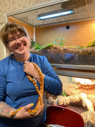 Zen Habitats animal care manager holding a corn snake. In the background are multiple 4x2x2 Zen Habitats reptile enclosures